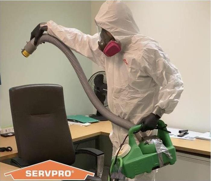 SERVPRO crew member in PPE cleaning an office